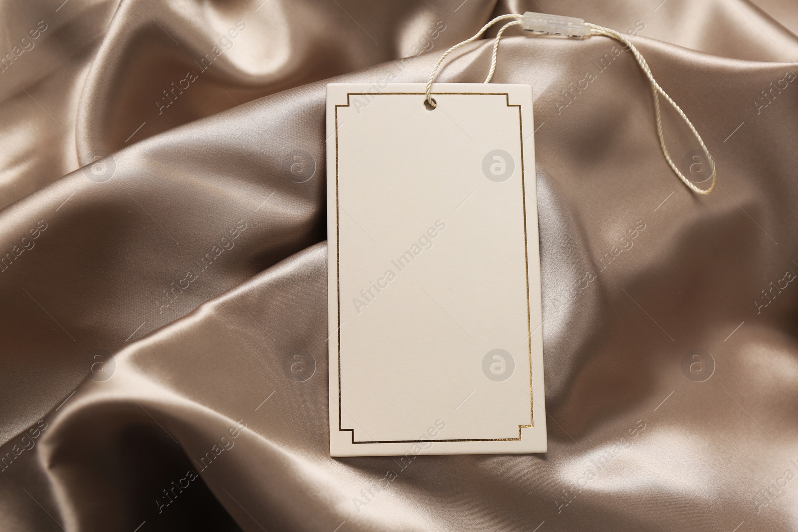 Photo of Blank white tag on silky fabric. Space for text