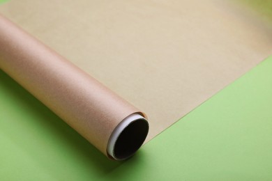 Photo of Roll of baking paper on light green background, closeup