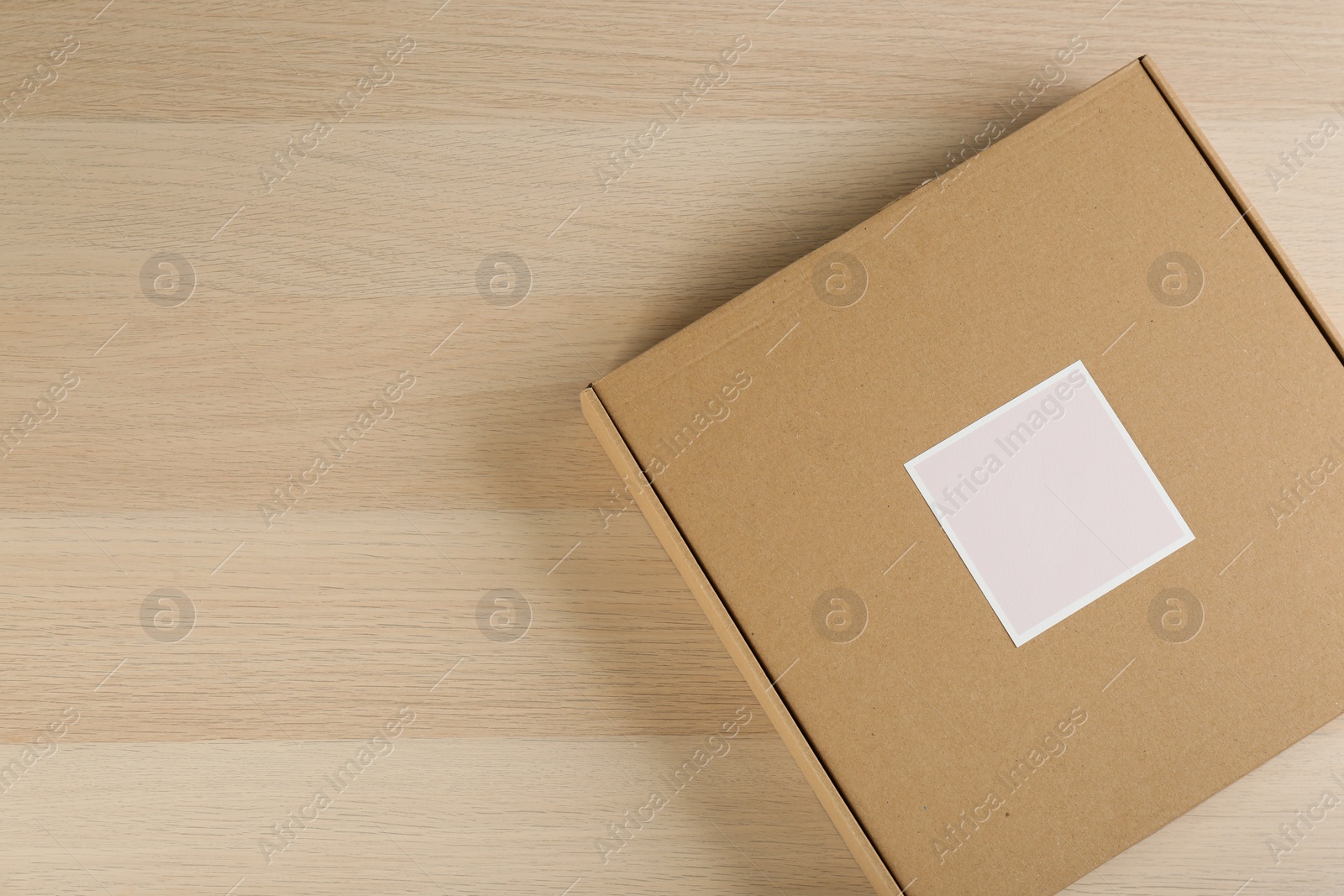 Photo of Cardboard box on wooden table, top view. Space for text