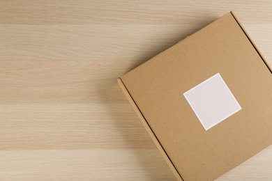 Photo of Cardboard box on wooden table, top view. Space for text