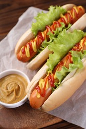 Tasty hot dogs with lettuce, ketchup and mustard on board