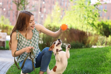 Photo of Young woman playing with adorable Jack Russell Terrier dog outdoors