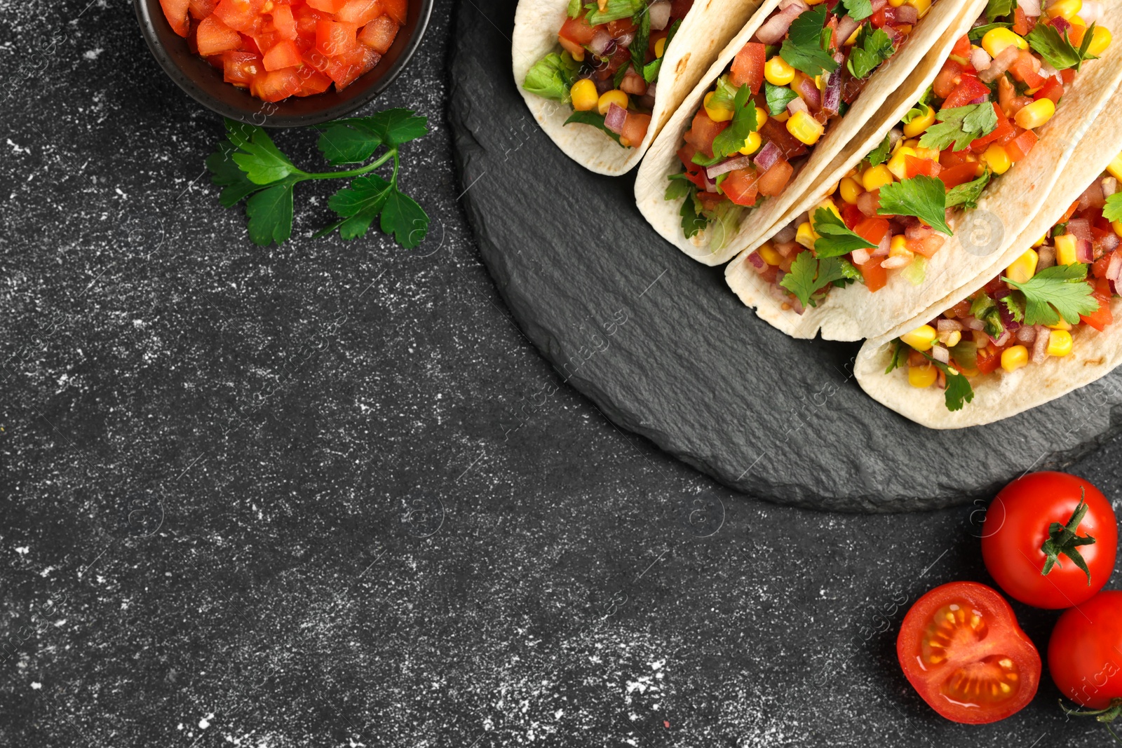 Photo of Tasty tacos with vegetables on black textured table, flat lay. Space for text