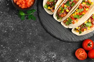 Photo of Tasty tacos with vegetables on black textured table, flat lay. Space for text