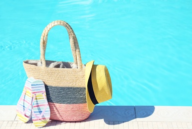 Bag with beach accessories near swimming pool on sunny day. Space for text