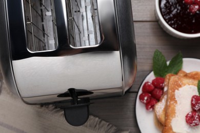 Photo of Toaster, sandwiches and raspberry jam on wooden table, flat lay