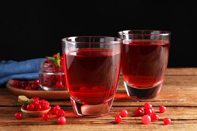 Photo of Tasty cranberry juice in glasses and fresh berries on wooden table