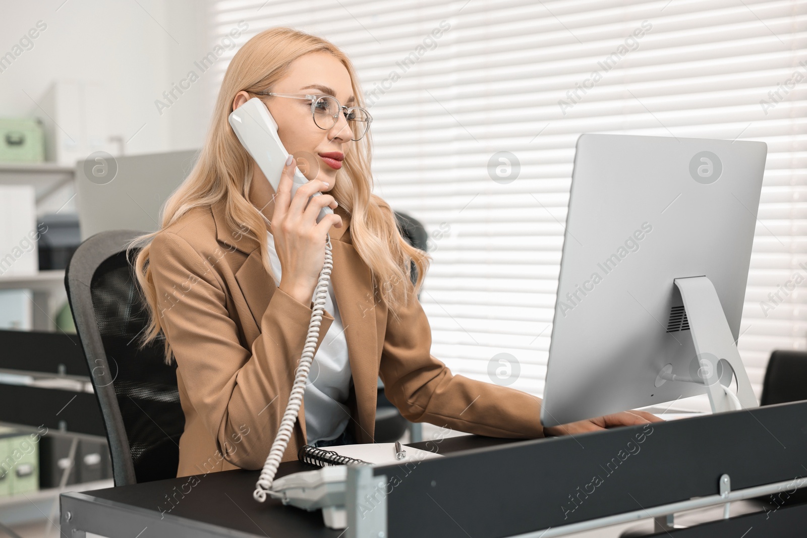 Photo of Secretary talking on phone at table in office