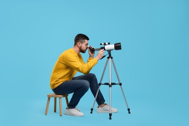Photo of Astronomer looking at stars through telescope on light blue background