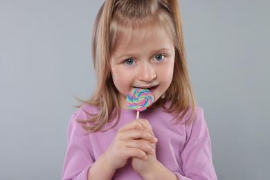 Photo of Portrait of cute girl with lollipop on light grey background