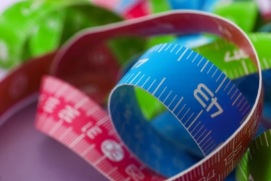 Kit of different measuring tapes on purple background, closeup