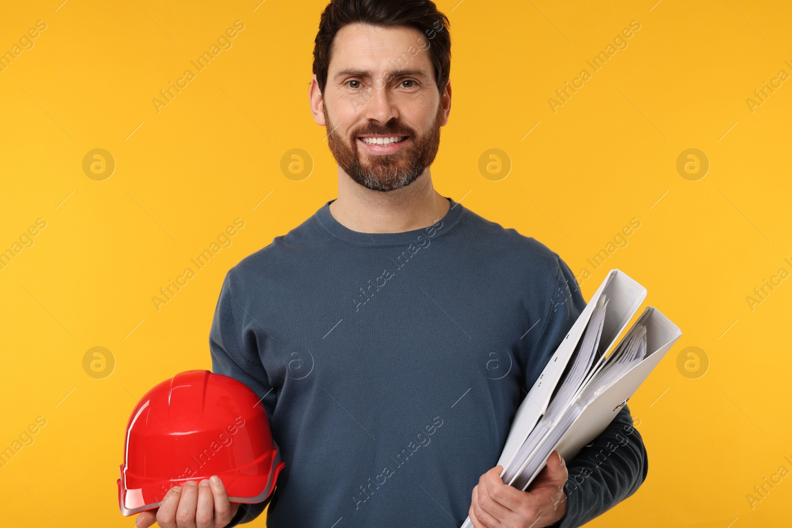 Photo of Architect with hard hat and folders on orange background
