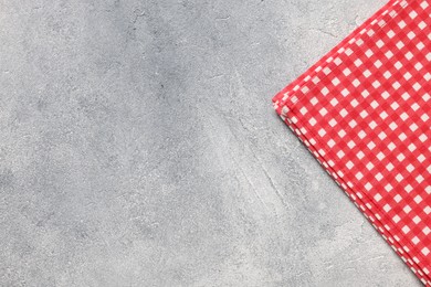 Red checkered tablecloth on light gray textured table, top view. Space for text
