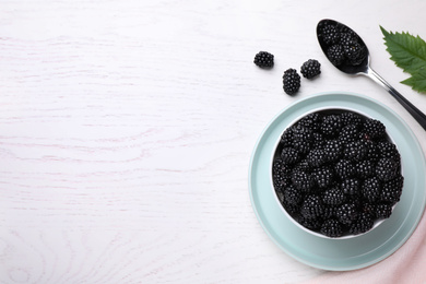 Flat lay composition with fresh ripe blackberries on white wooden table. Space for text