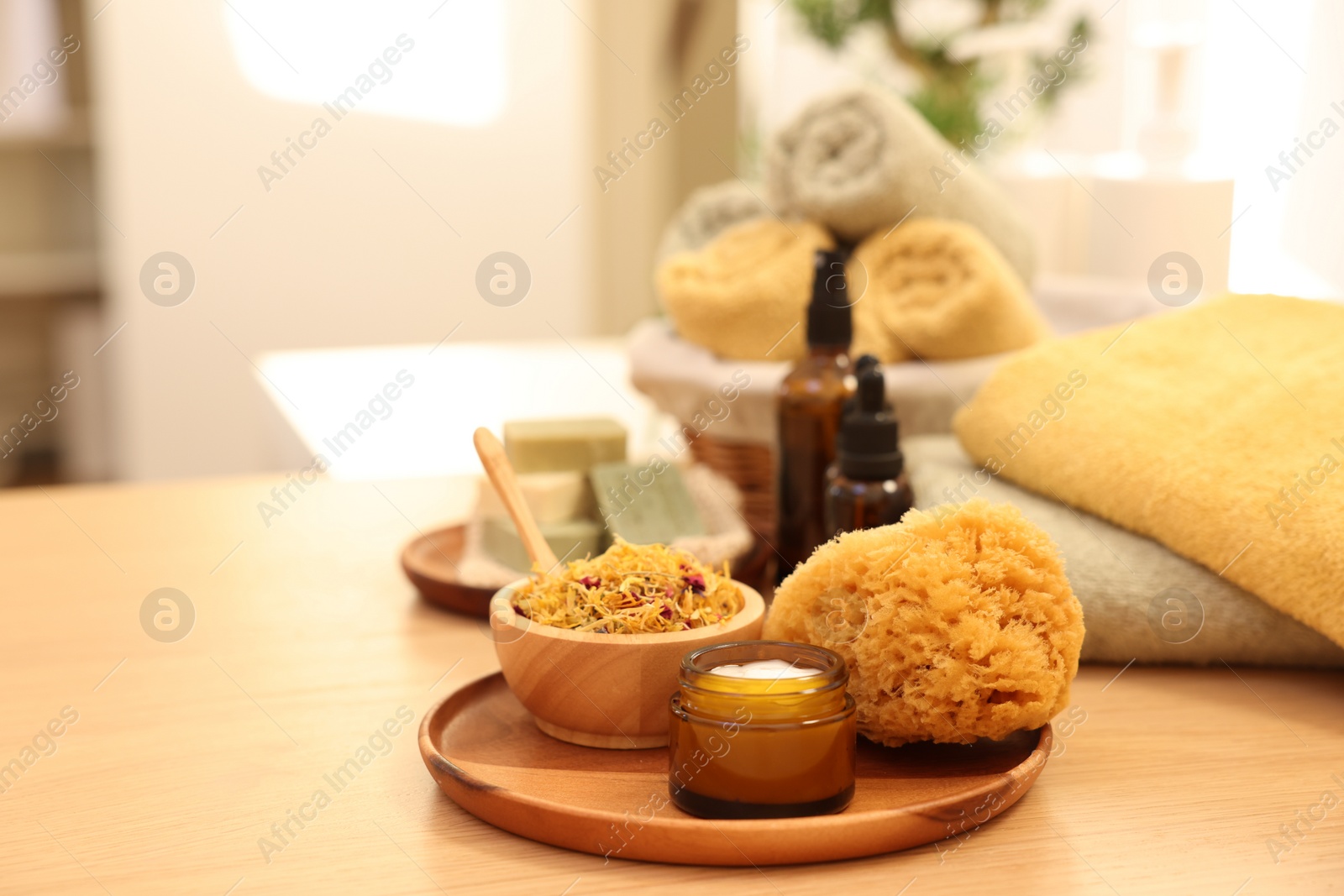 Photo of Dry flowers, loofah and jar with cream on wooden table indoors, space for text. Spa time