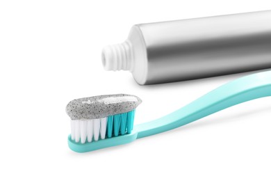 Photo of Tube of charcoal toothpaste and brush on white background