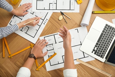 People working with construction drawings and tools  at wooden table, top view