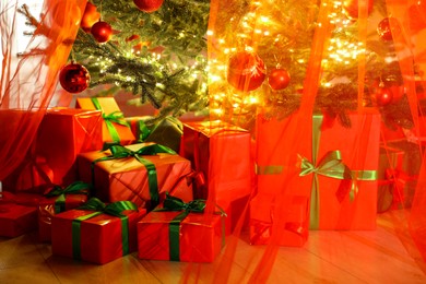 Photo of Beautifully wrapped gift boxes under Christmas tree indoors