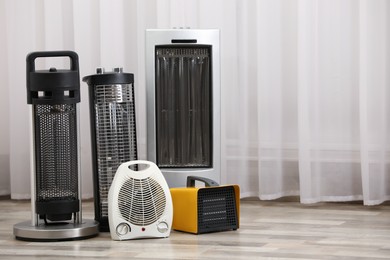 Photo of Different modern electric heaters on floor in room
