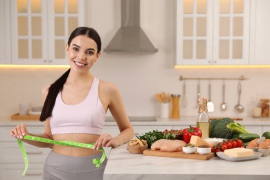 Photo of Happy woman measuring waist with tape in kitchen. Keto diet