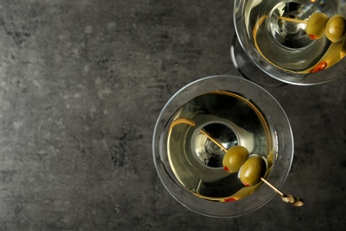 Photo of Glasses of Classic Dry Martini with olives on grey table, flat lay. Space for text