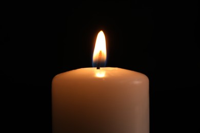 Photo of Burning candle in darkness, closeup. Memory day