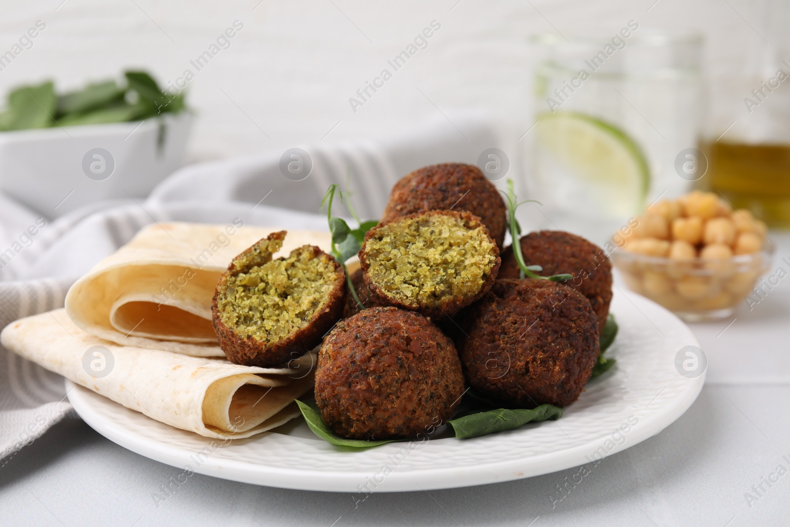 Photo of Delicious falafel balls, herbs and lavash on white table