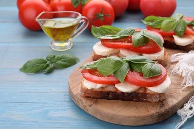 Delicious Caprese sandwiches with mozzarella, tomatoes and basil on light blue wooden table. Space for text