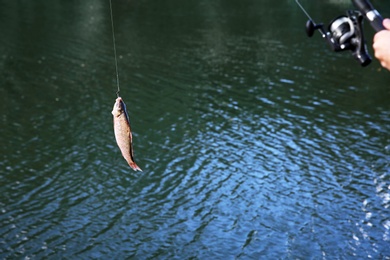 Photo of Man with rod fishing at riverside, closeup. Recreational activity