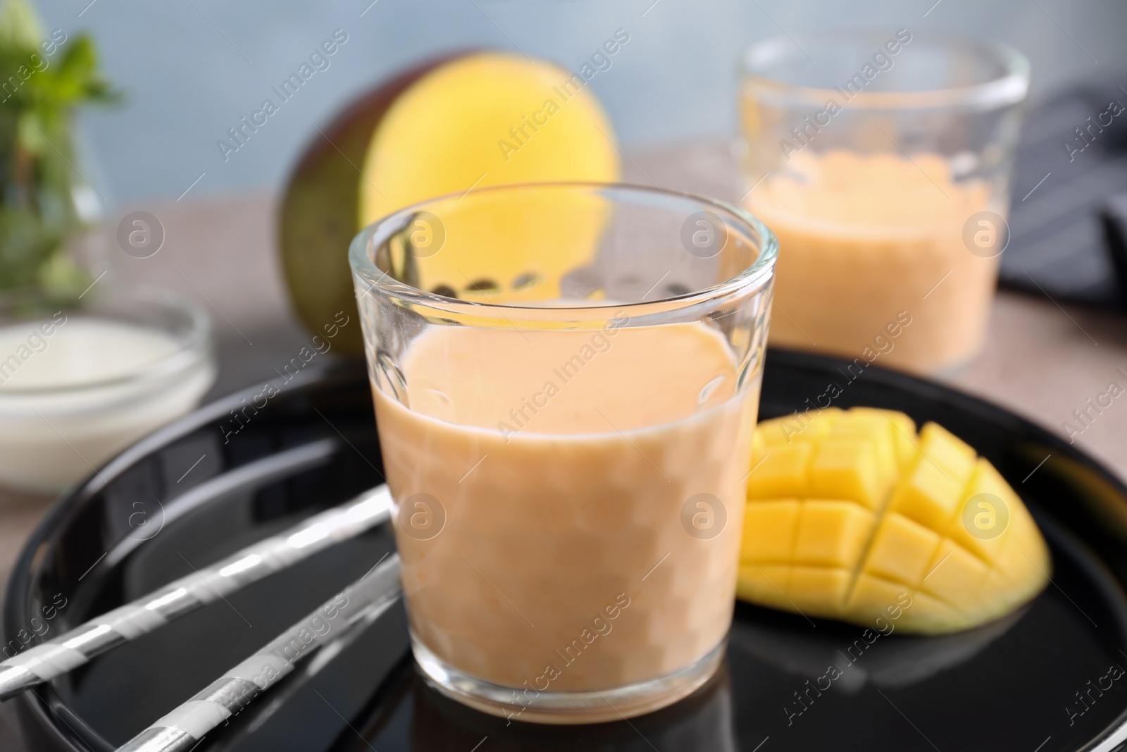 Photo of Glass with healthy detox smoothie and mango on tray