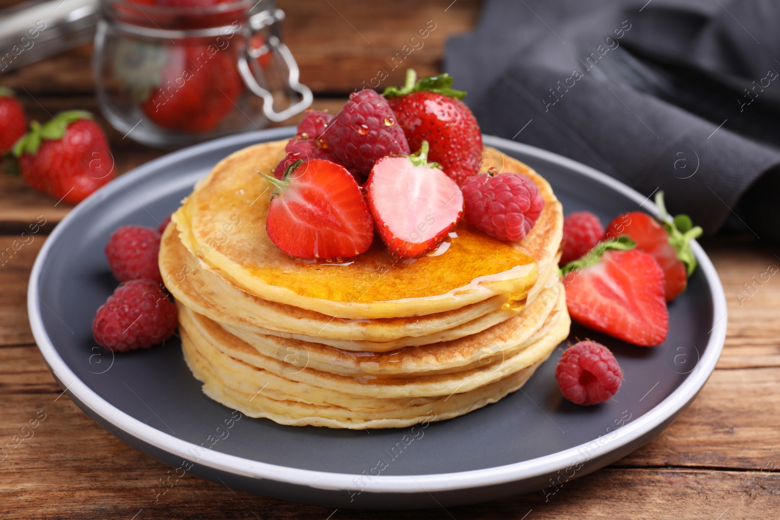 Photo of Tasty pancakes with fresh berries and honey on wooden table, closeup