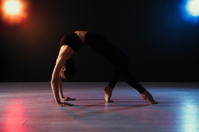 Young professional acrobat exercising in dark studio