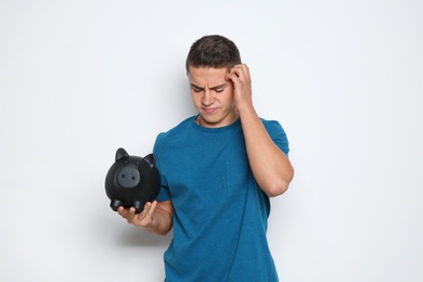 Photo of Teenage boy with piggy bank on white background
