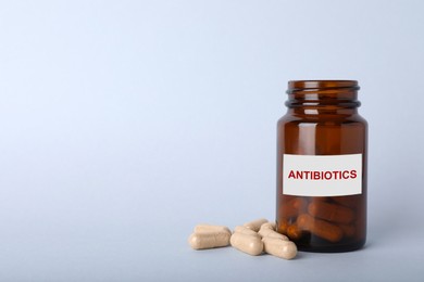 Image of Bottle with antibiotic pills on light grey background, space for text