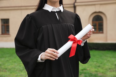 Photo of Student with diploma after graduation ceremony outdoors, closeup