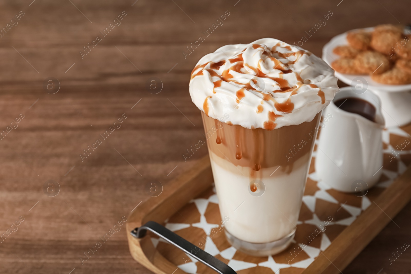 Photo of Glass of caramel macchiato on wooden table, space for text