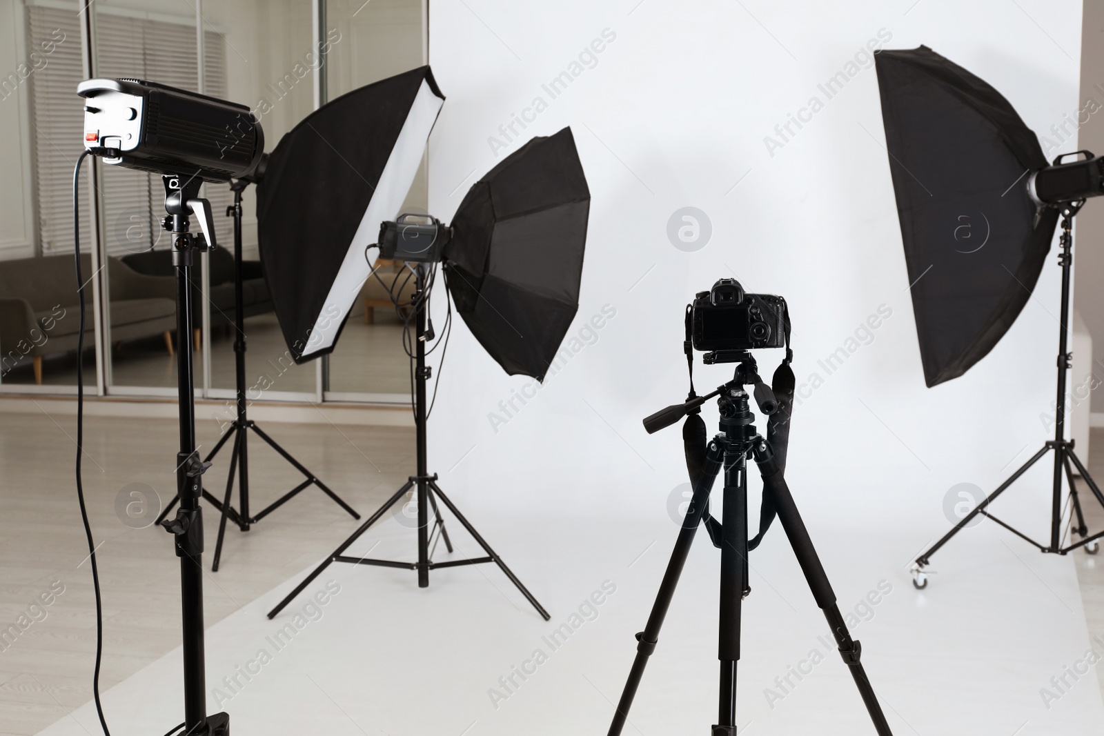 Photo of Tripod with camera and professional lighting equipment in photo studio