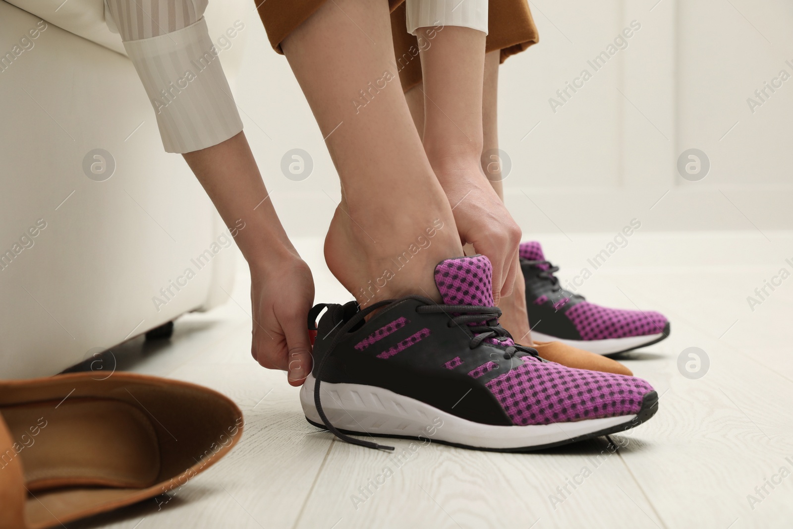 Photo of Woman changing shoes on sofa in office, closeup