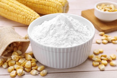 Photo of Bowl with corn starch, ripe cobs and kernels on wooden table, closeup