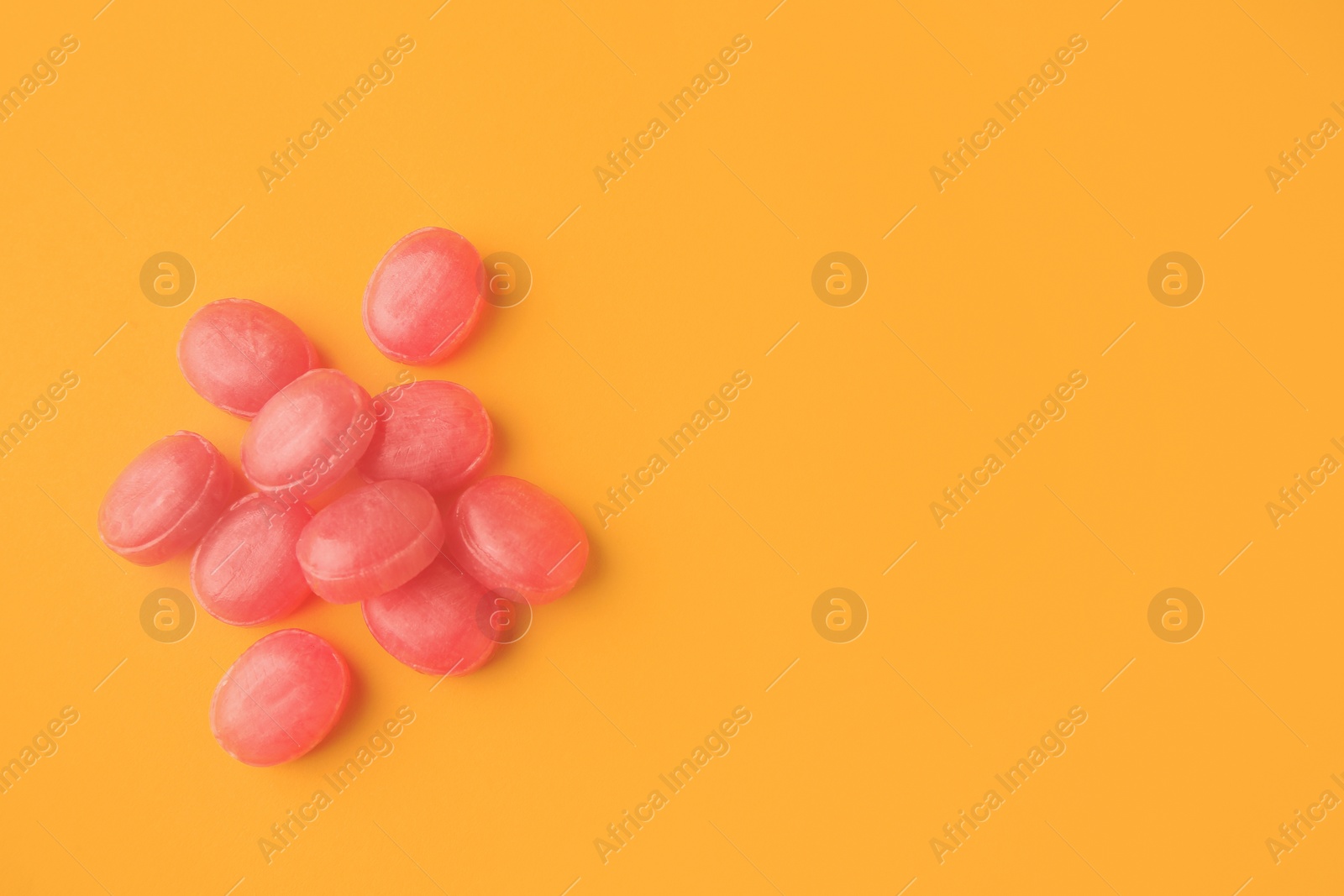 Photo of Many pink cough drops on orange background, flat lay. Space for text