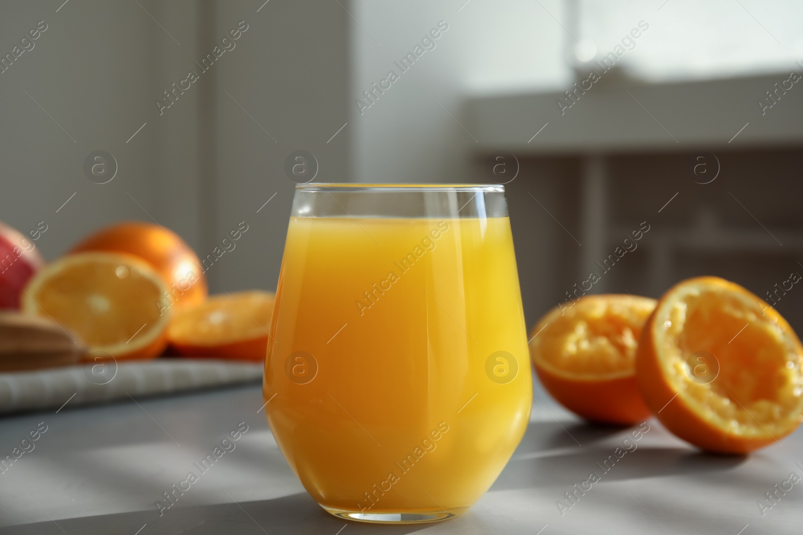 Photo of Freshly made juice and oranges on grey table, closeup