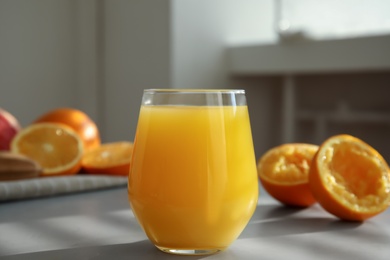 Freshly made juice and oranges on grey table, closeup