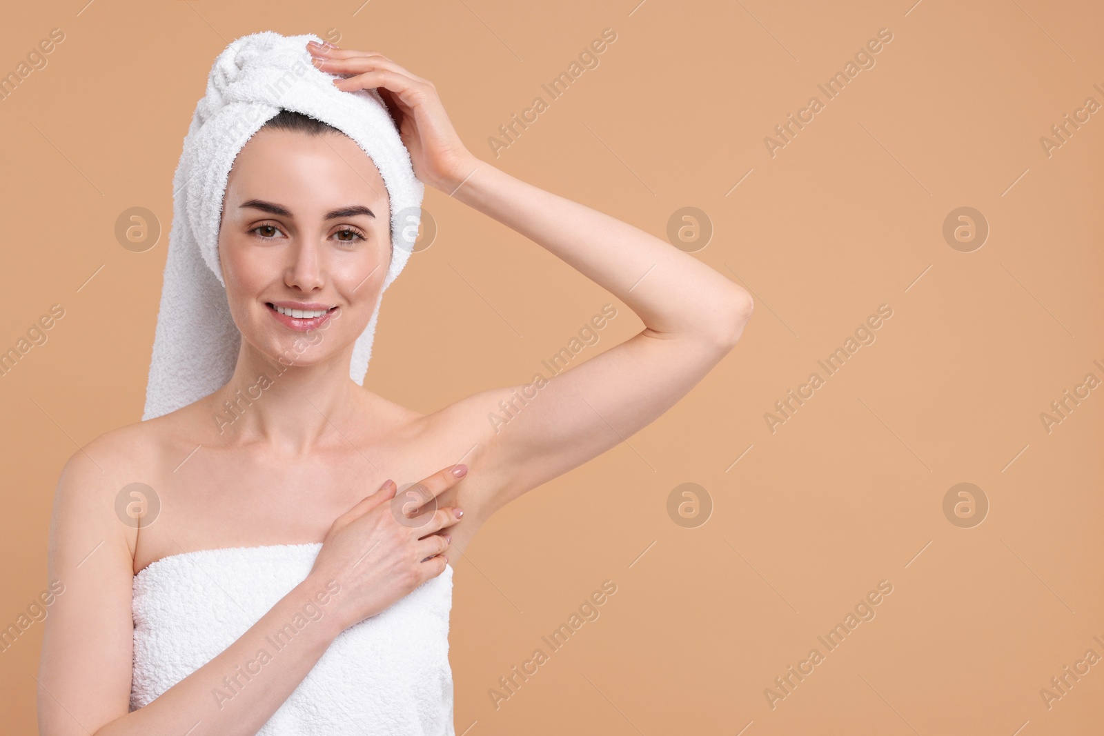 Photo of Beautiful woman showing armpit with smooth clean skin on beige background, space for text