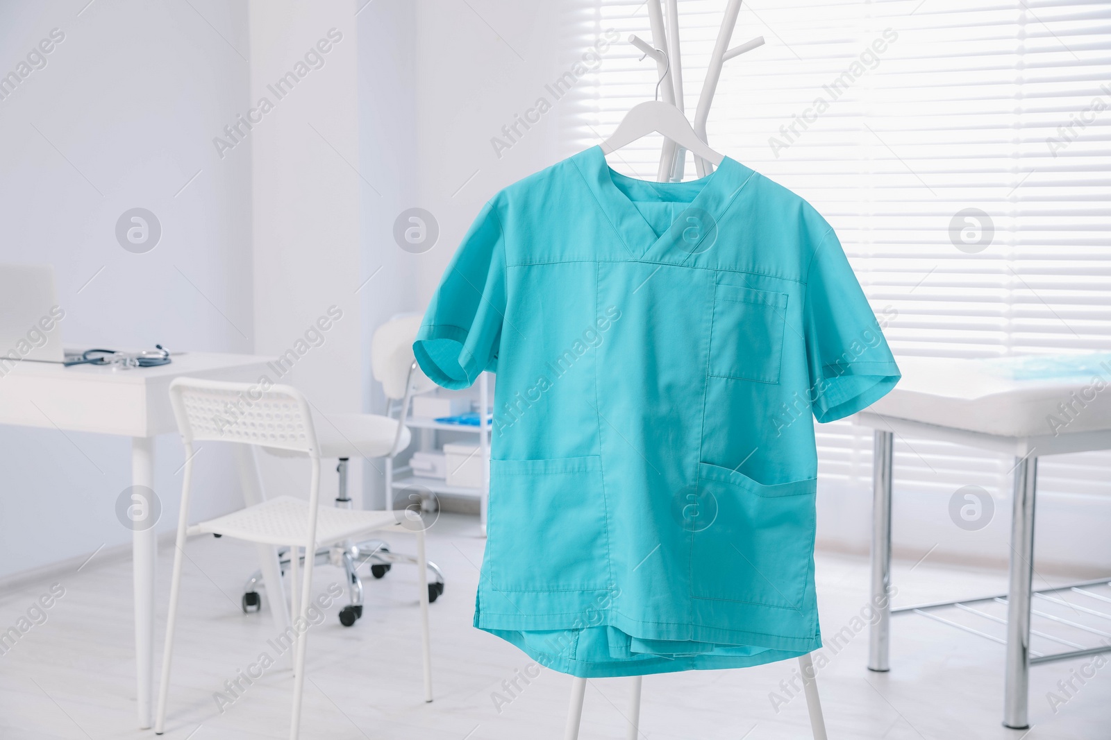 Photo of Turquoise medical uniform on rack in clinic. Space for text