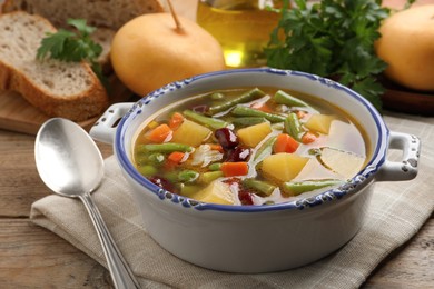 Photo of Bowl of tasty turnip soup with napkin and spoon on wooden table