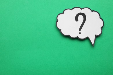 Paper speech bubble with question mark on green background, top view. Space for text