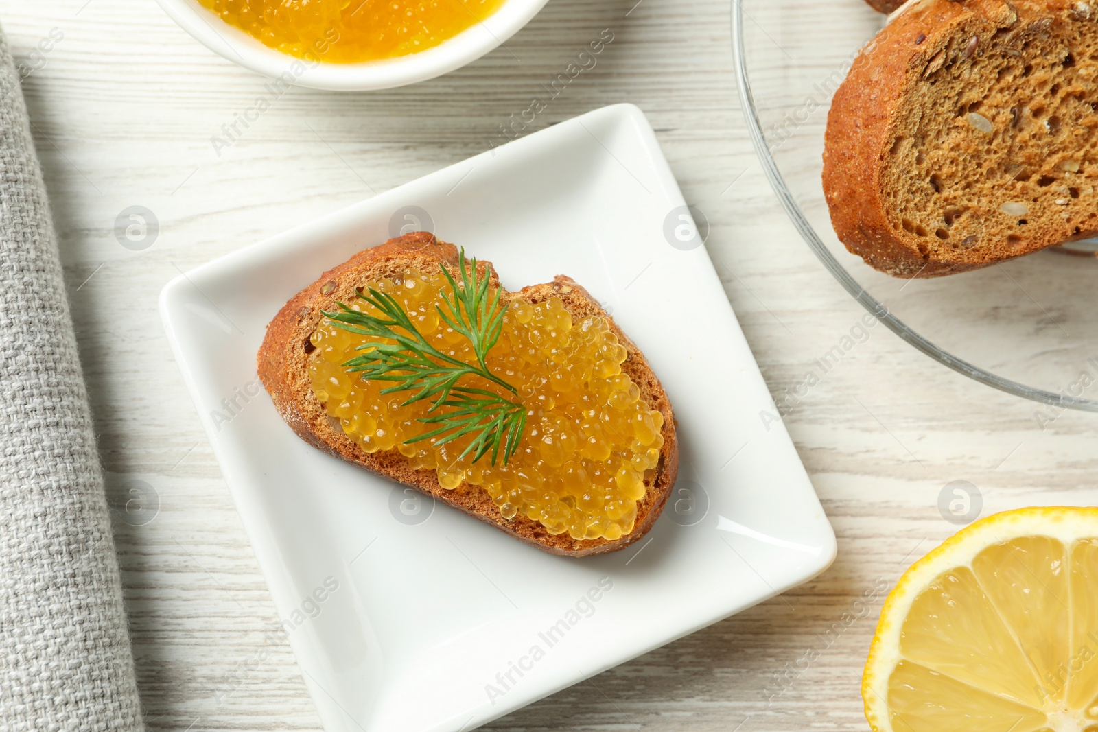 Photo of Slice of bread with pike caviar on white wooden table, flat lay