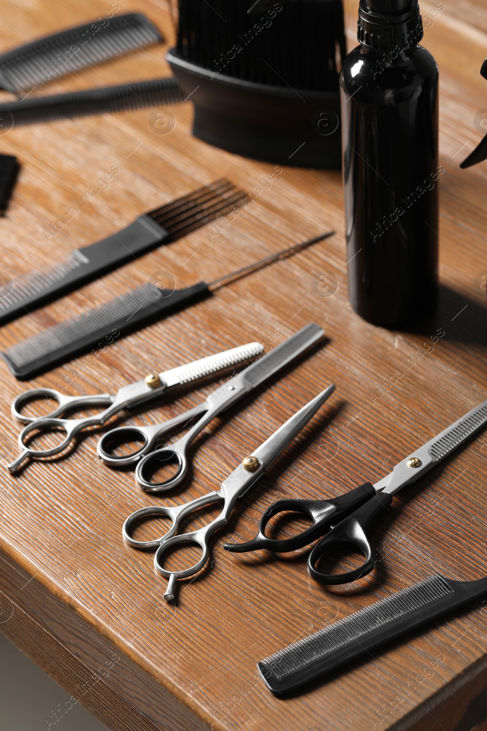 Photo of Hairdresser tools. Different scissors and combs on wooden table, closeup