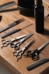 Hairdresser tools. Different scissors and combs on wooden table, closeup