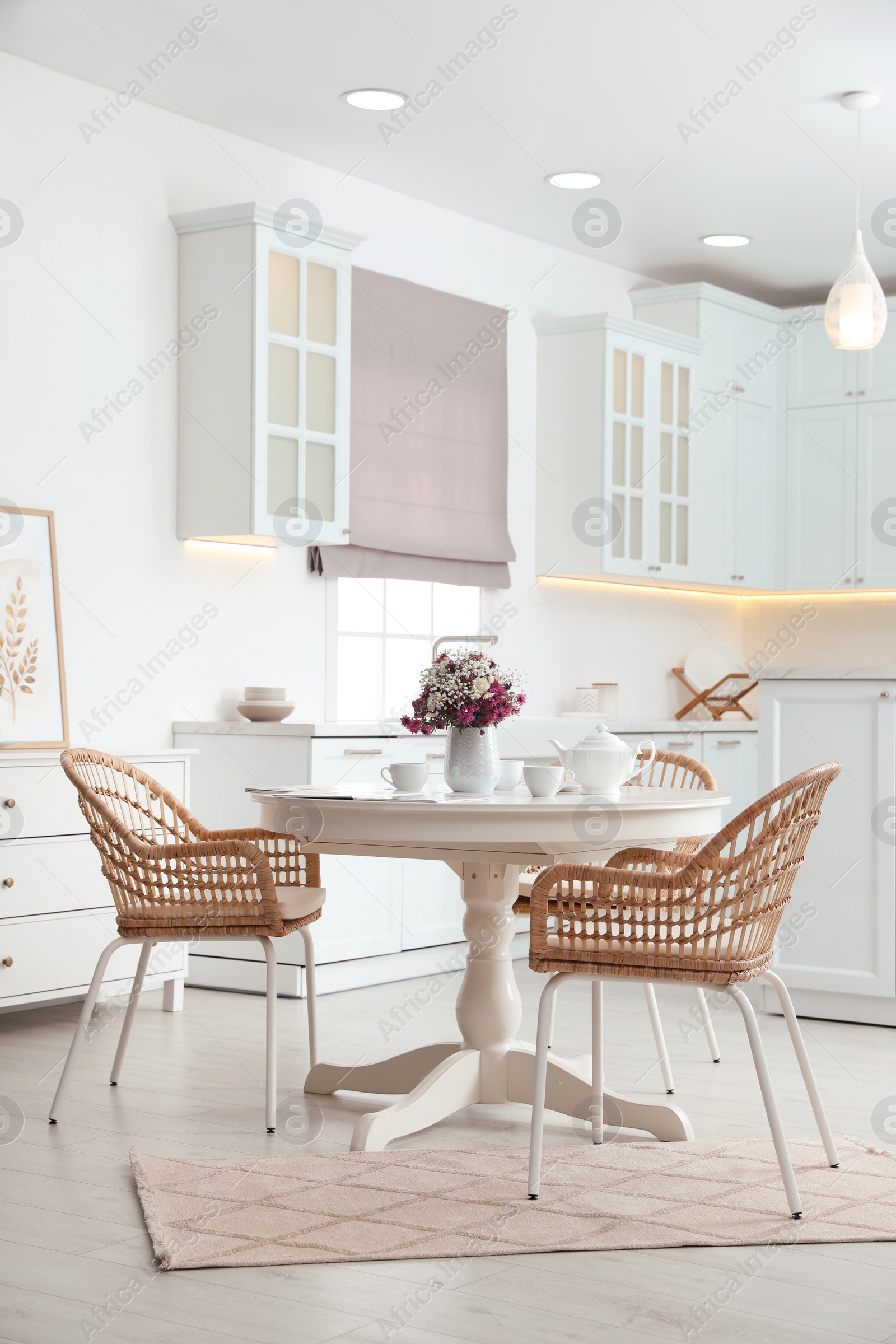 Photo of Dining room interior with tea set on round table and wicker chairs